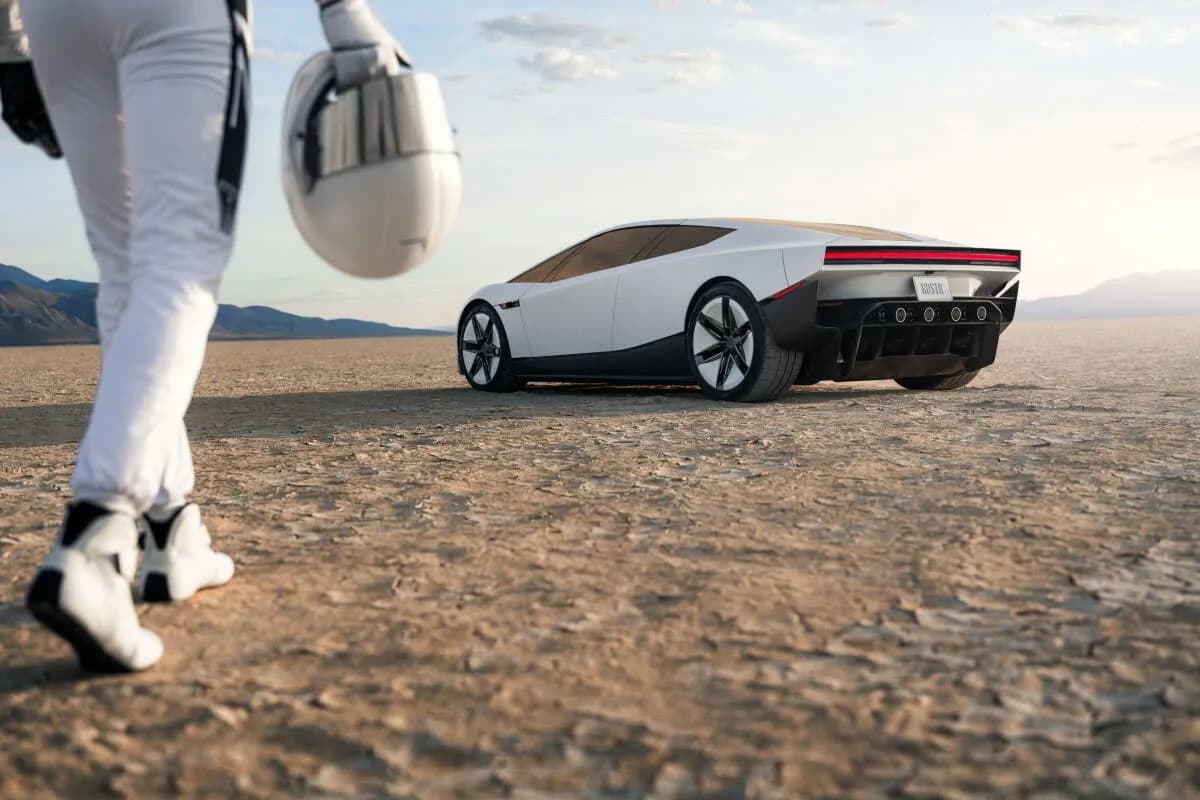 A white electric supercar parked on a cracked dry lakebed at golden hour, with a driver in a white racing suit walking toward it holding a helmet